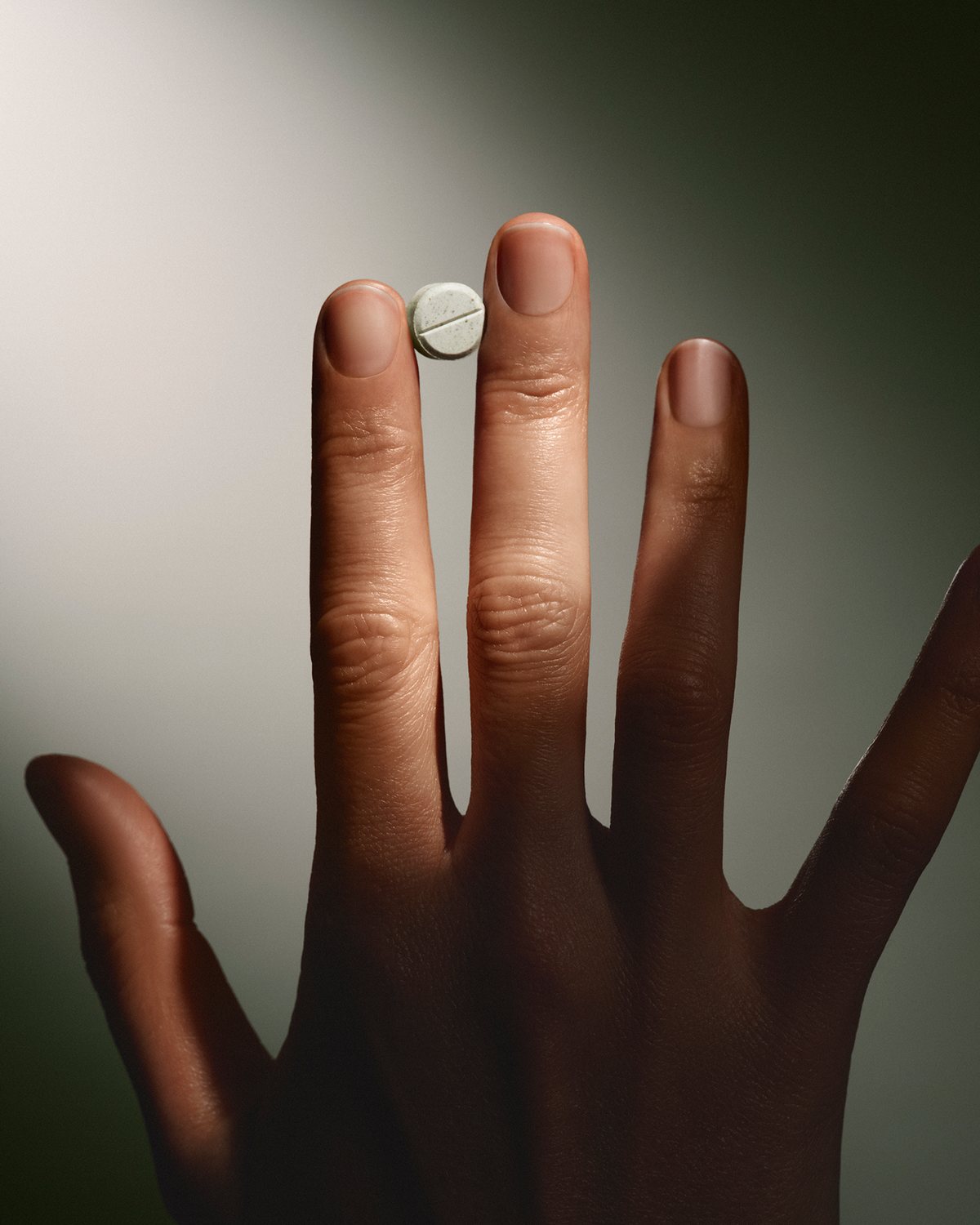 Hand holding a small white mint against a neutral background