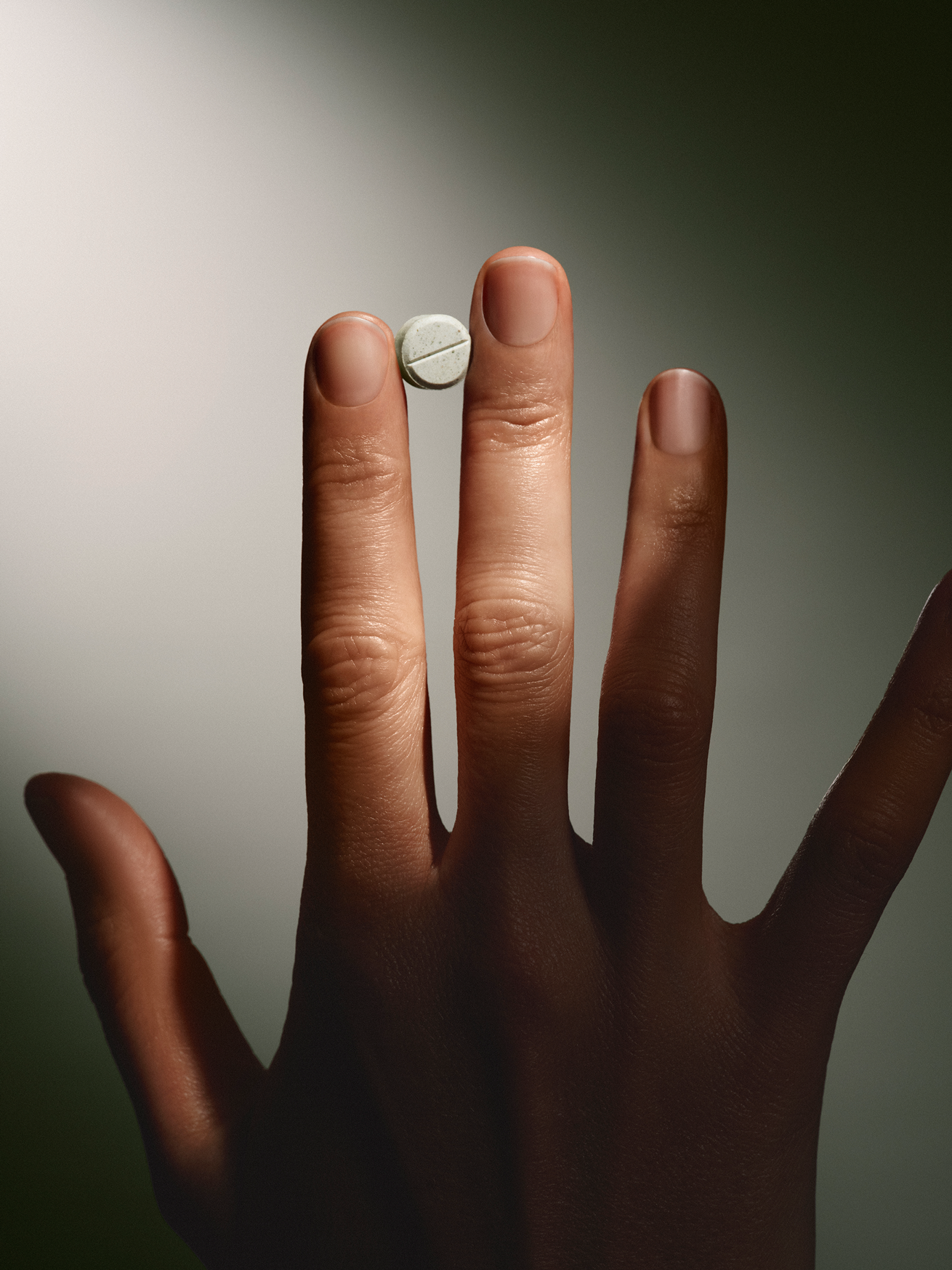 Hand holding a small white mint against a neutral background