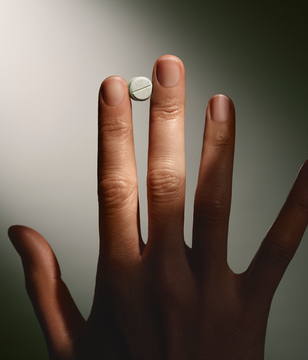 Hand holding a small white mint against a neutral background