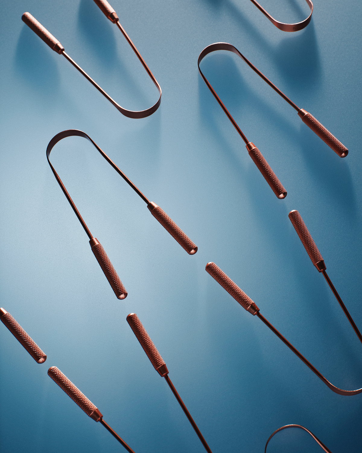 Copper tongue scrapers on a blue background