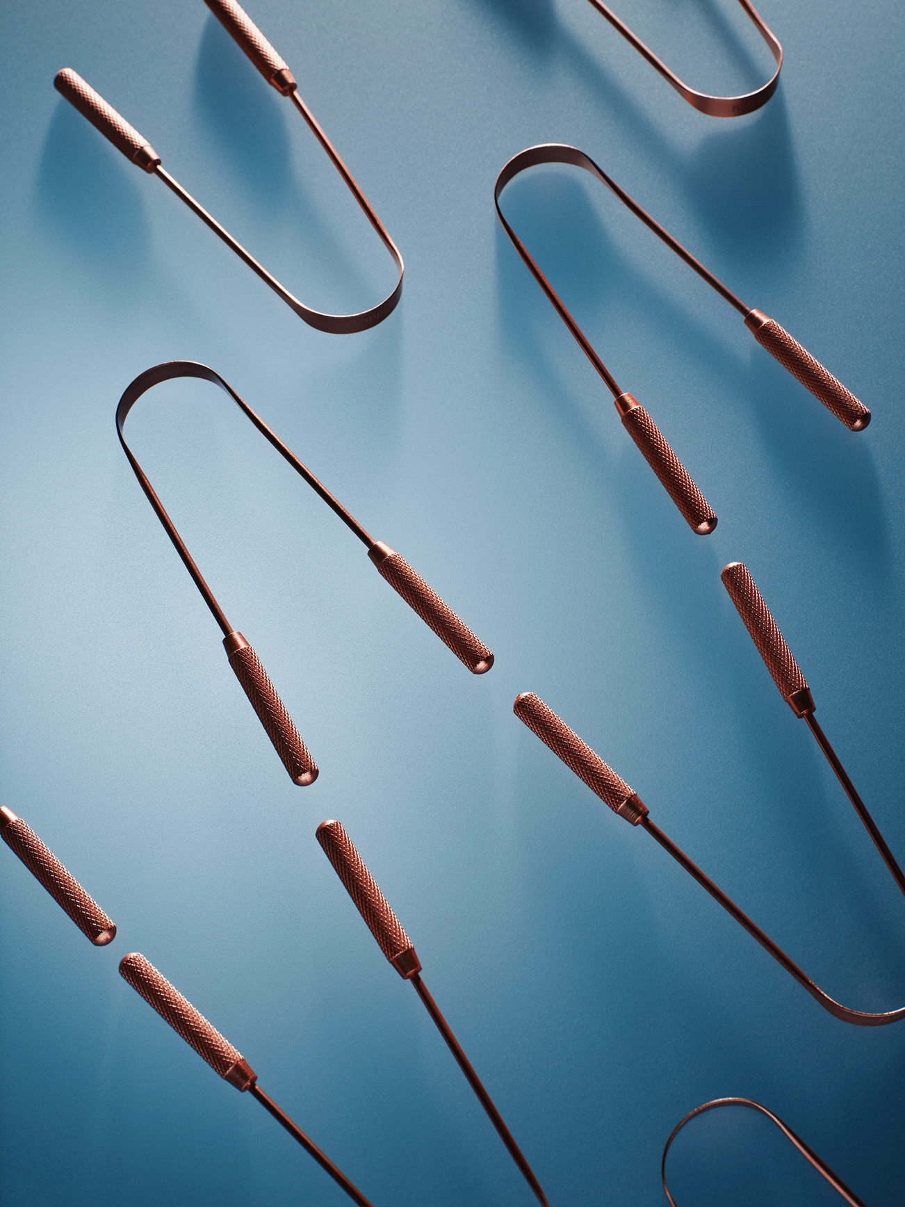 Copper tongue scrapers on a blue background