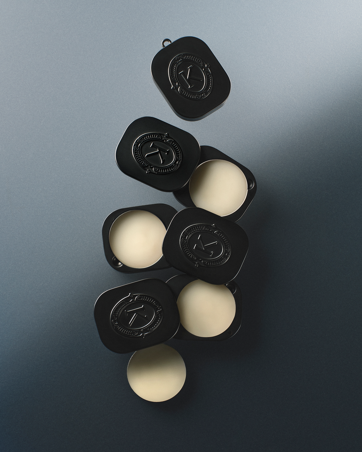Grey lip balm compacts with white balm filling a gray background