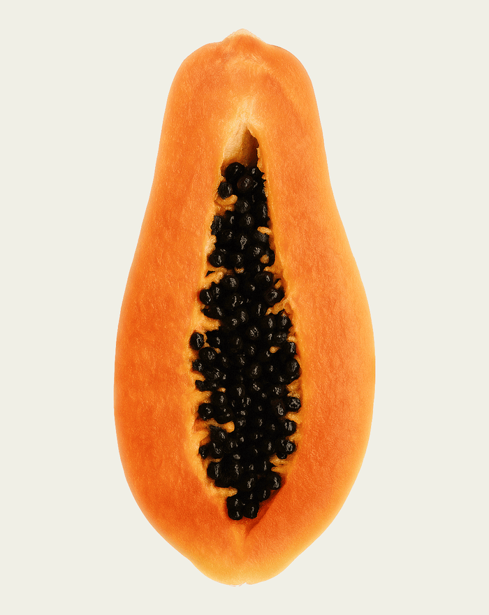 Half-cut papaya with black seeds on a light beige background