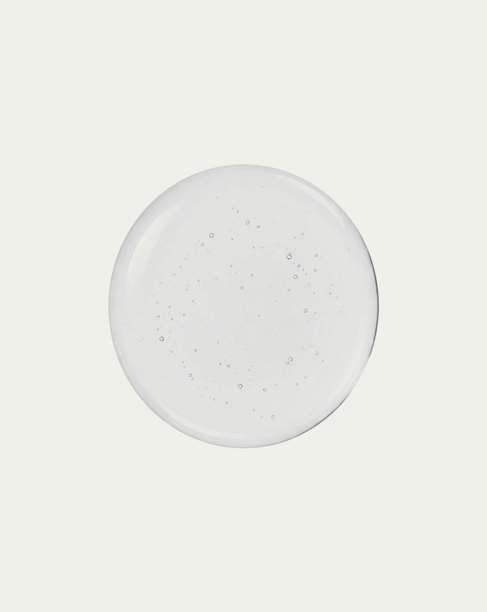 Round clear glue dot with subtle texture on a light gray background