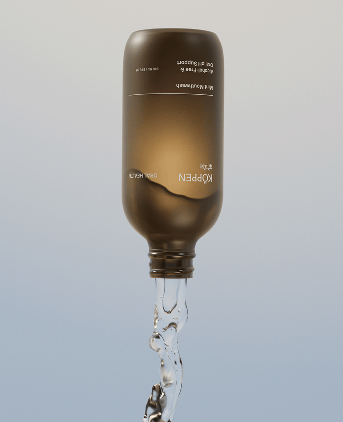Brown amber frosted bottle with clear liquid pouring out on a light gray background