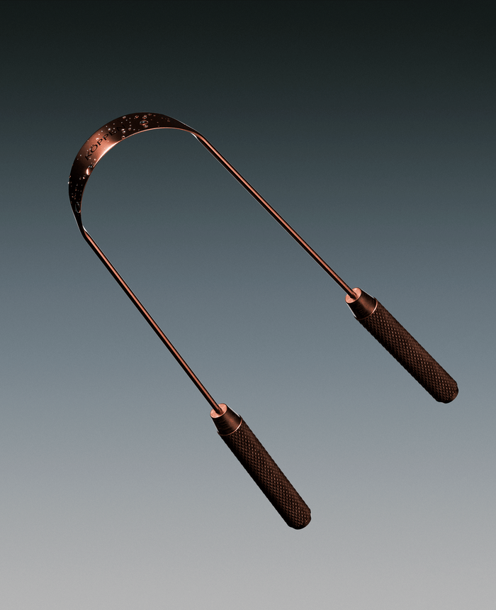 Copper tongue scraper on light grey background