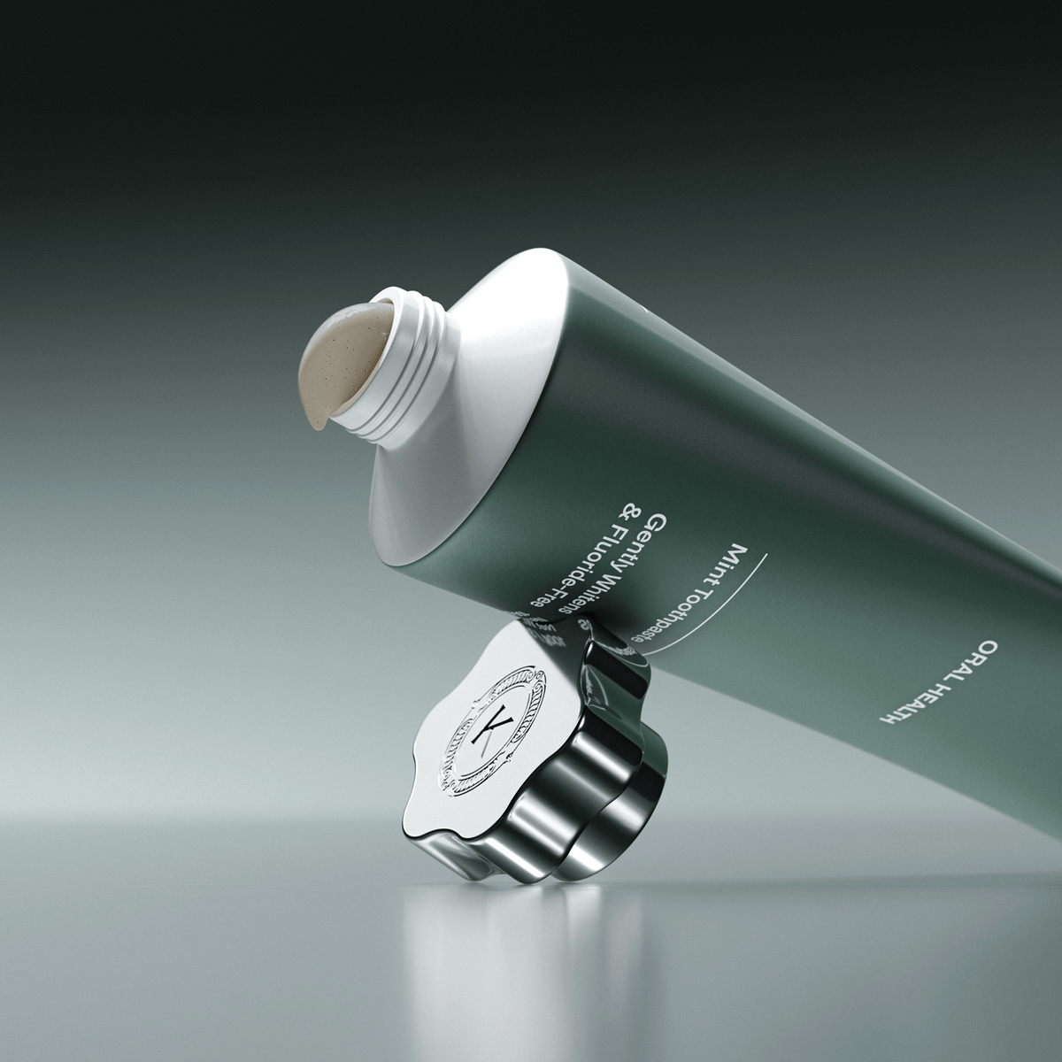 Green and white toothpaste tube with a silver cap on a gray background